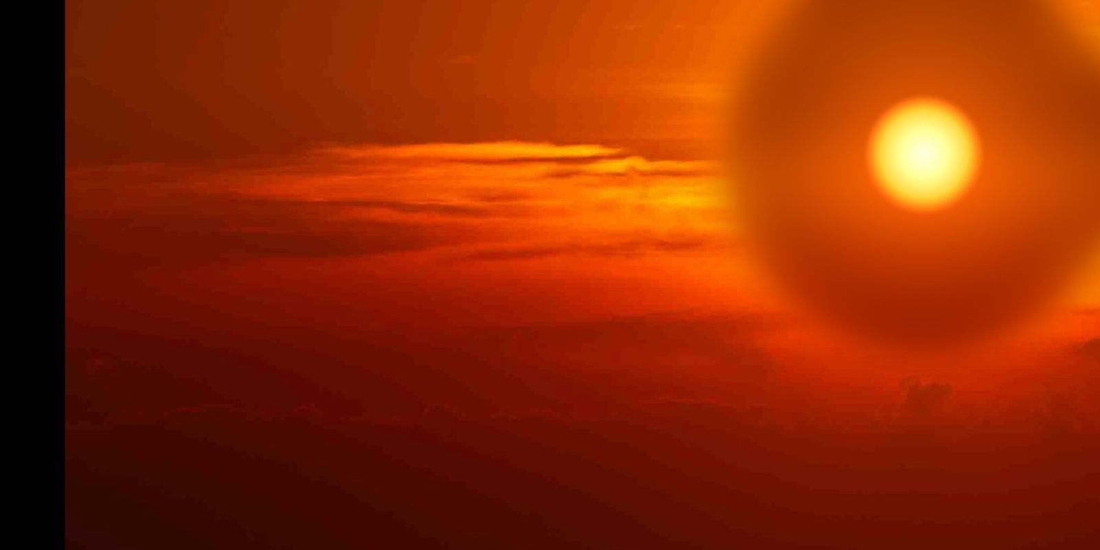 The sun low over the ocean, a single bright disc in a sky of amber and burnt orange cloud